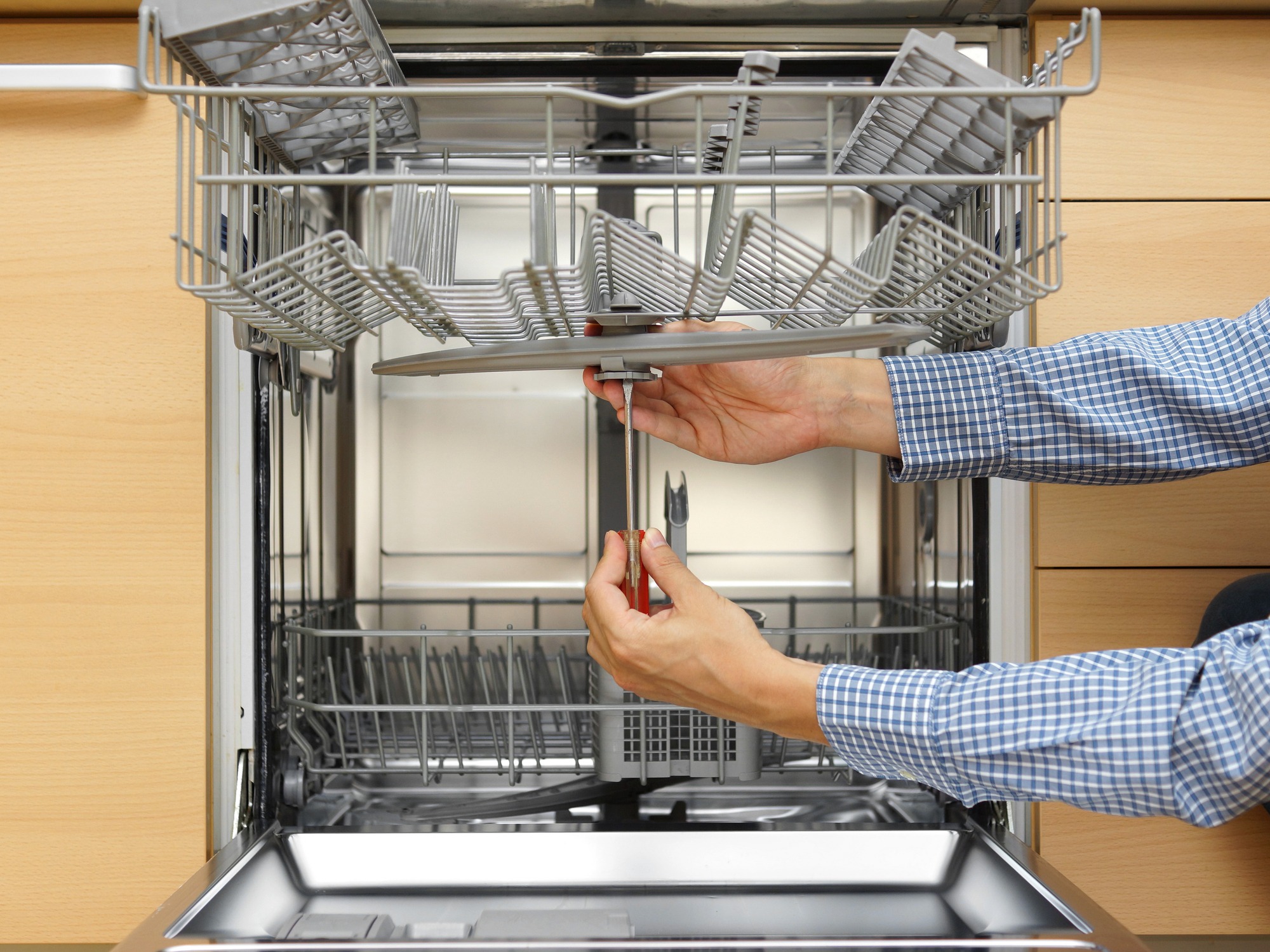 Handyman repairing a dishwasher with screwdriver