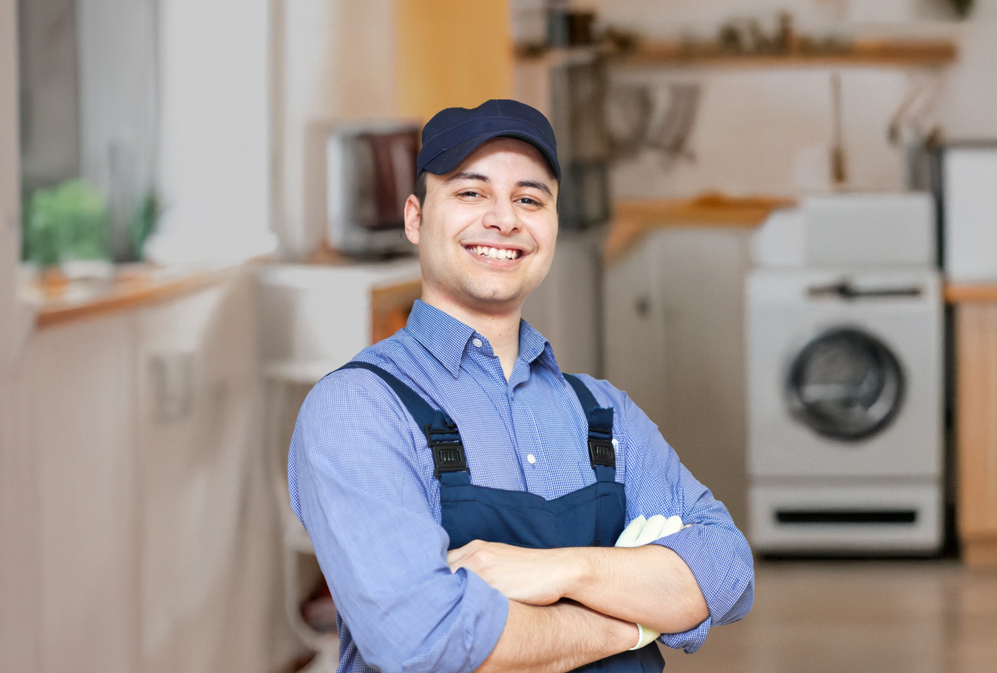 A man wearing a blue shirt and hat stands in a modern kitchen